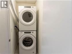 Washroom with estacked washer and dryer and baseboards -