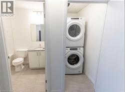 Laundry room featuring stacked washer / drying machine and light tile patterned floors -