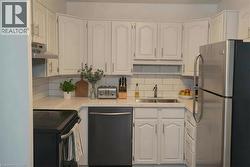 Kitchen with stainless steel appliances, white cabinetry, under cabinet range hood, and decorative backsplash -