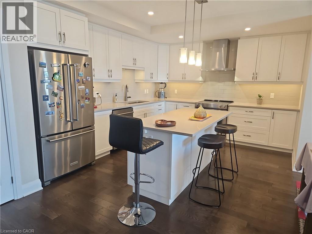Kitchen with white cabinets, a kitchen island, appliances with stainless steel finishes, wall chimney exhaust hood, and recessed lighting - 249 Grey Silo Road Unit# 301, Waterloo, ON - Indoor Photo Showing Kitchen With Stainless Steel Kitchen