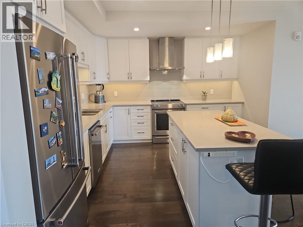 Kitchen featuring high quality appliances, wall chimney exhaust hood, pendant lighting, white cabinetry, and recessed lighting - 249 Grey Silo Road Unit# 301, Waterloo, ON - Indoor Photo Showing Kitchen With Stainless Steel Kitchen