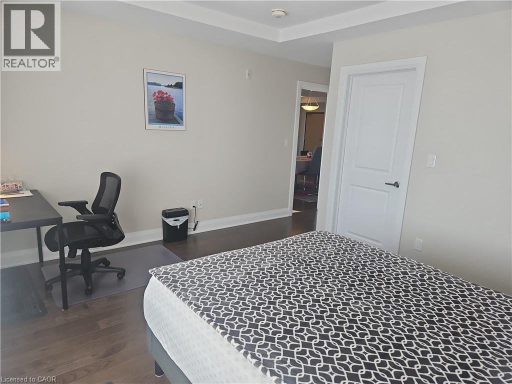 Bedroom with an office area and dark wood finished floors - 249 Grey Silo Road Unit# 301, Waterloo, ON - Indoor Photo Showing Bedroom