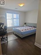 Bedroom with an office area and dark wood-style floors -