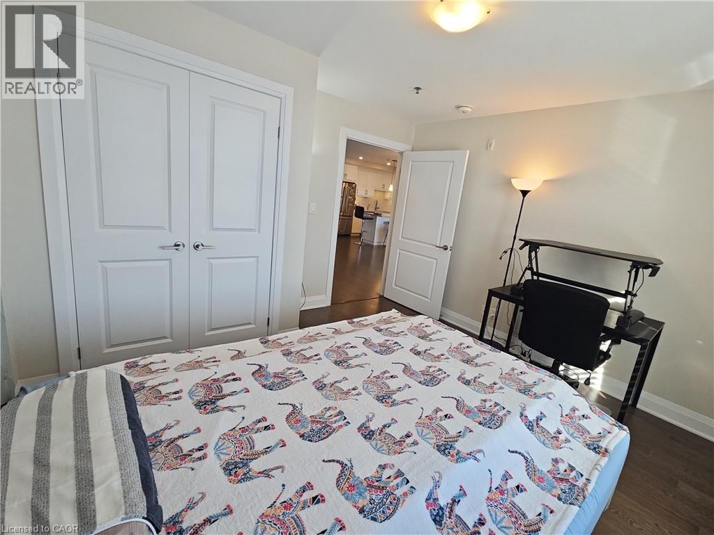 Bedroom with dark wood-type flooring, a closet, and freestanding refrigerator - 249 Grey Silo Road Unit# 301, Waterloo, ON - Indoor Photo Showing Bedroom
