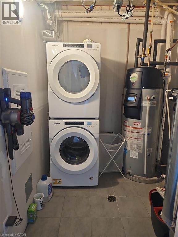 Washroom with water heater and estacked washer and dryer - 249 Grey Silo Road Unit# 301, Waterloo, ON - Indoor Photo Showing Laundry Room