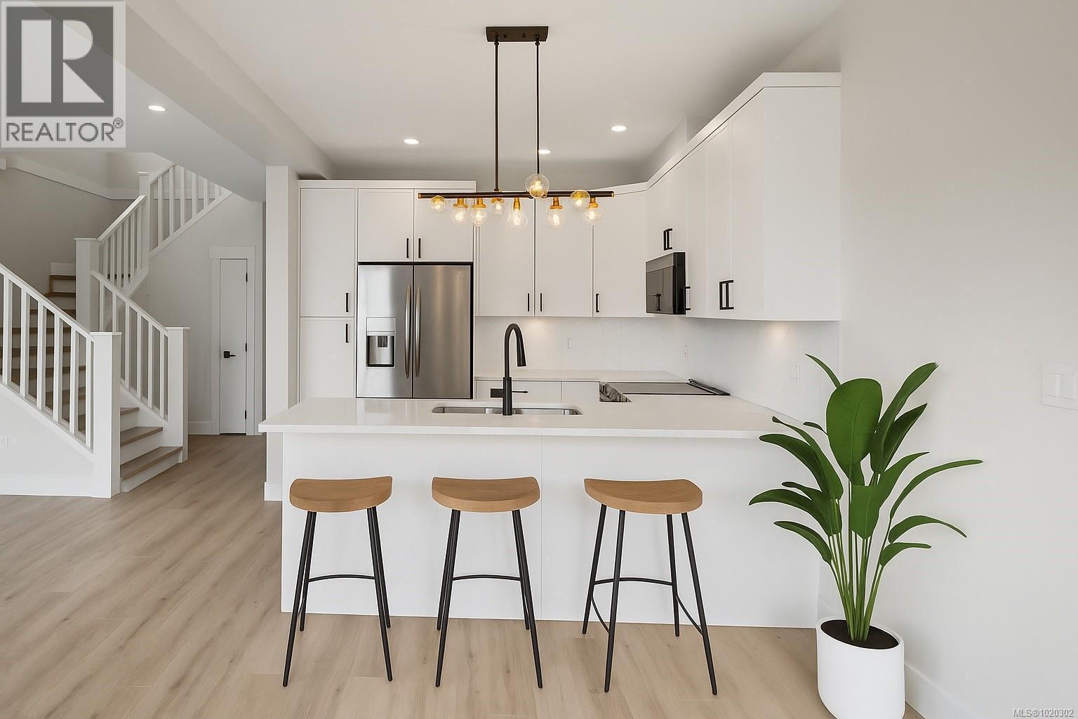Kitchen featuring a peninsula, white cabinets, stainless steel appliances, pendant lighting, and a breakfast bar - A 6521 Noblewood Pl, Sooke, BC - Indoor Photo Showing Kitchen