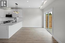 Kitchen featuring backsplash, hanging light fixtures, a peninsula, light stone countertops, and recessed lighting -