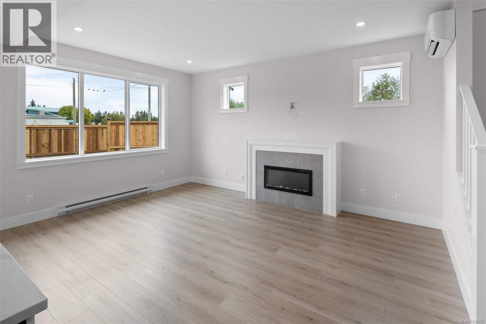 Unfurnished living room with a baseboard heating unit, light wood finished floors, recessed lighting, an AC wall unit, and a glass covered fireplace - A 6521 Noblewood Pl, Sooke, BC - Indoor Photo Showing Living Room With Fireplace