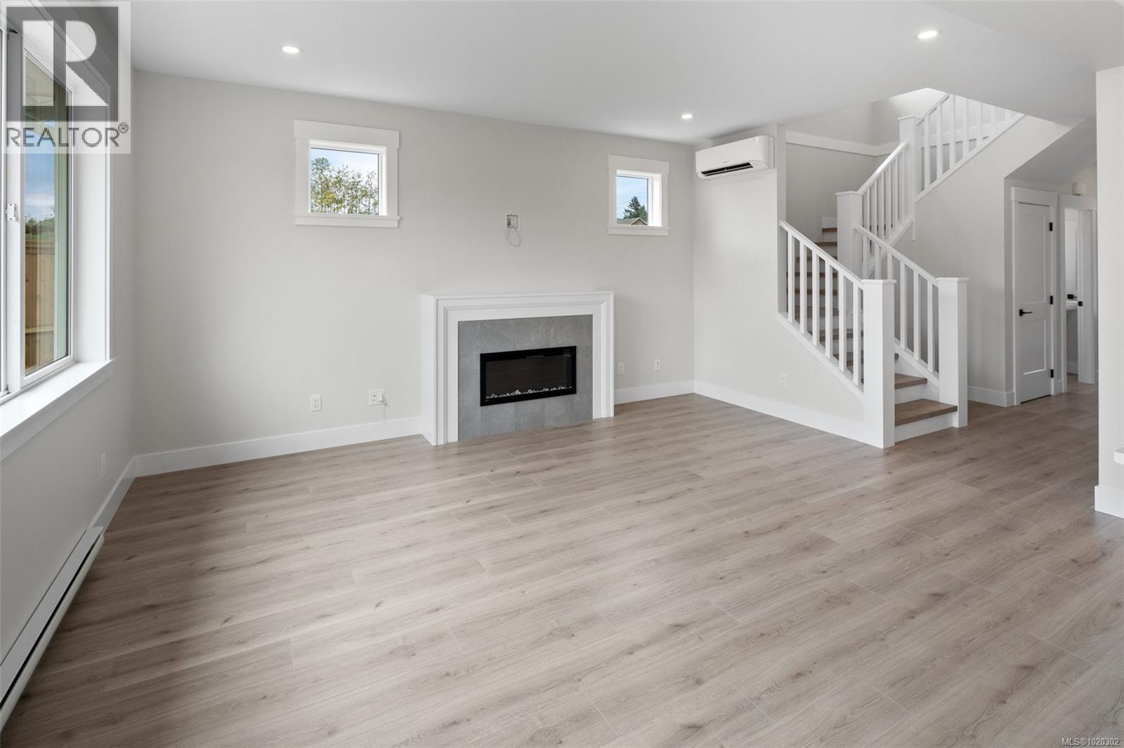 Unfurnished living room with baseboard heating, light wood-style floors, recessed lighting, stairs, and a high end fireplace - A 6521 Noblewood Pl, Sooke, BC - Indoor Photo Showing Living Room With Fireplace