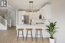 Kitchen featuring a peninsula, white cabinets, stainless steel appliances, pendant lighting, and a breakfast bar -