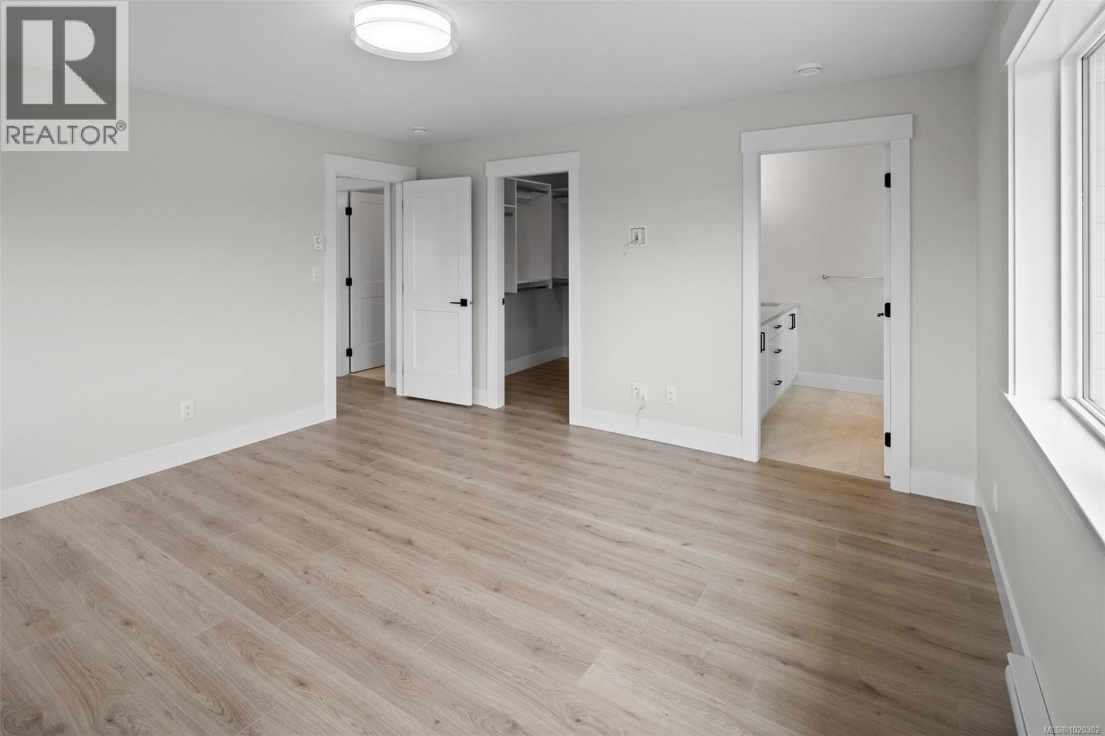 Unfurnished bedroom featuring a walk in closet, light wood-type flooring, ensuite bathroom, and a baseboard heating unit - A 6521 Noblewood Pl, Sooke, BC - Indoor Photo Showing Other Room