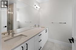 Bathroom featuring double vanity, a shower stall, and light tile patterned flooring -