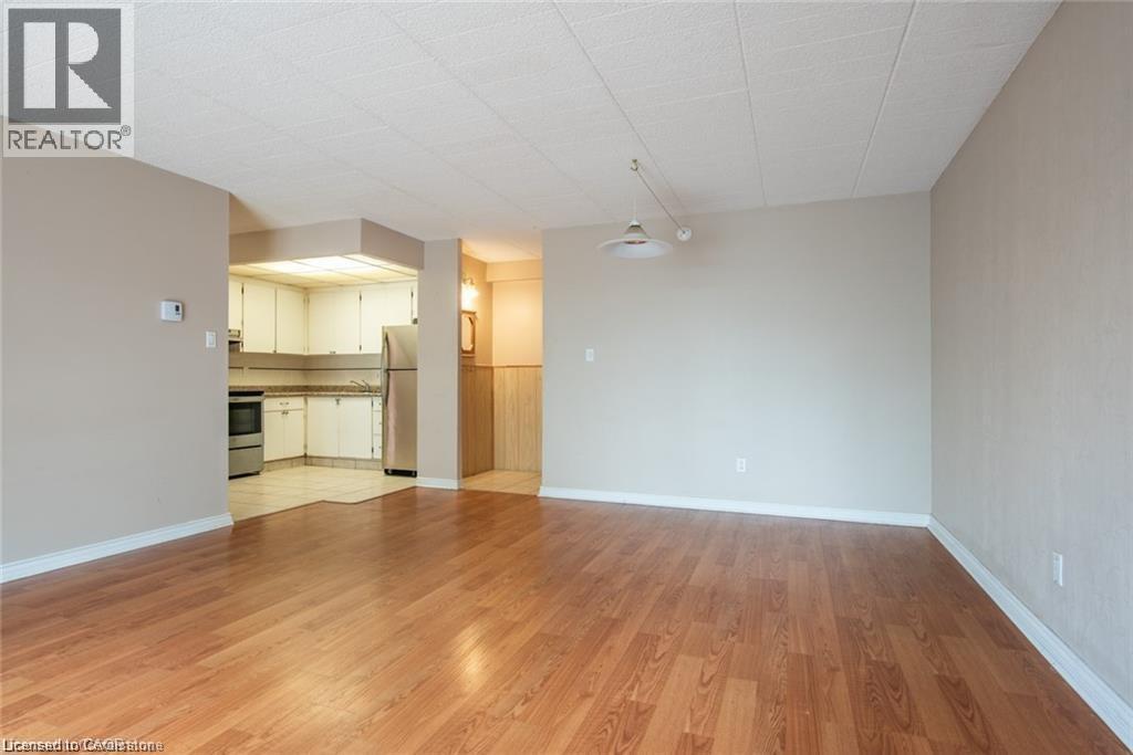 Unfurnished living room featuring light wood-style flooring and baseboards - 71 Vanier Drive Unit# 211, Kitchener, ON - Indoor