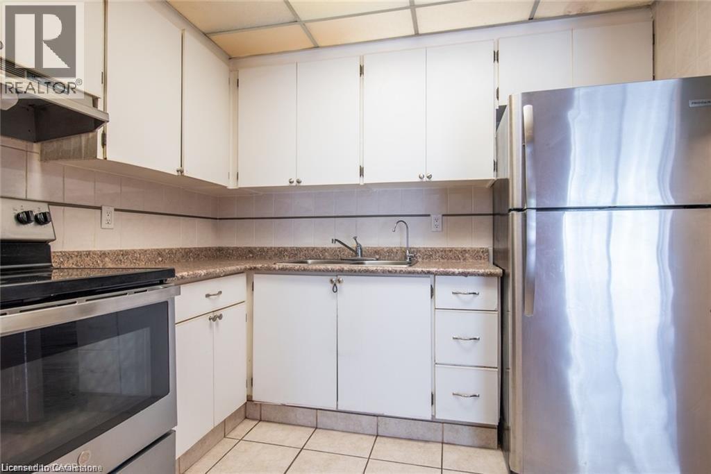 Kitchen with stainless steel appliances, white cabinetry, extractor fan, and light tile patterned floors - 71 Vanier Drive Unit# 211, Kitchener, ON - Indoor Photo Showing Kitchen