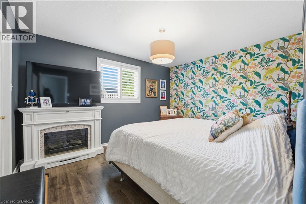 Bedroom with an accent wall, dark wood-type flooring, and a fireplace - 14 Dunton Lane, Paris, ON - Indoor Photo Showing Bedroom