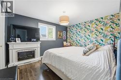 Bedroom with an accent wall, dark wood-type flooring, and a fireplace -