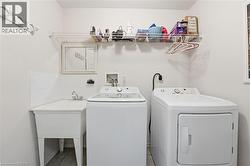 Laundry room with independent washer and dryer and light tile patterned flooring -