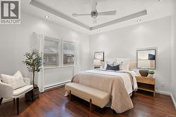 Bedroom with a tray ceiling, a textured ceiling, dark wood-style floors, baseboard heating, and ceiling fan -