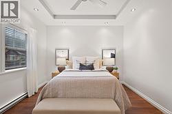 Bedroom featuring baseboard heating, dark wood finished floors, a textured ceiling, a raised ceiling, and recessed lighting -