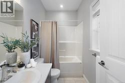 Bathroom with shower / bath combo with shower curtain, vanity, and light tile patterned floors -