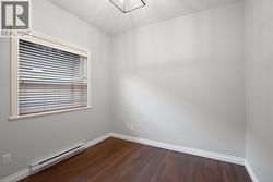 Empty room with a baseboard heating unit, dark wood-style flooring, and a textured ceiling -