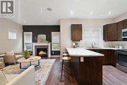 Kitchen with dark brown cabinetry, open floor plan, a breakfast bar, a tile fireplace, and recessed lighting -