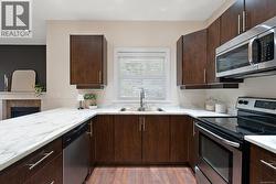 Kitchen with dark brown cabinetry, stainless steel appliances, light wood finished floors, and modern cabinets -