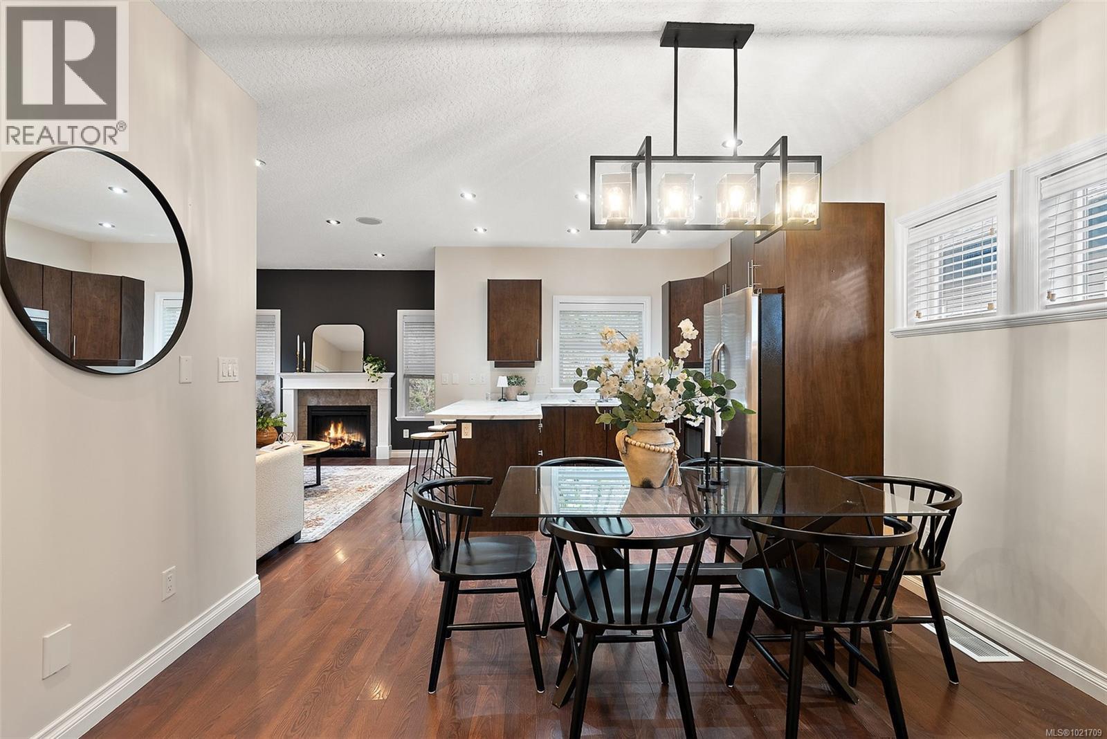 Dining room with a tile fireplace and dark wood-style floors - 883 Wild Ridge Way, Langford, BC - Indoor Photo Showing Dining Room With Fireplace
