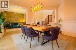 Dining space featuring light wood-type flooring, a wainscoted wall, a chandelier, and stairs -
