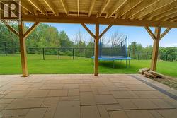 Fenced backyard with a trampoline and a patio -