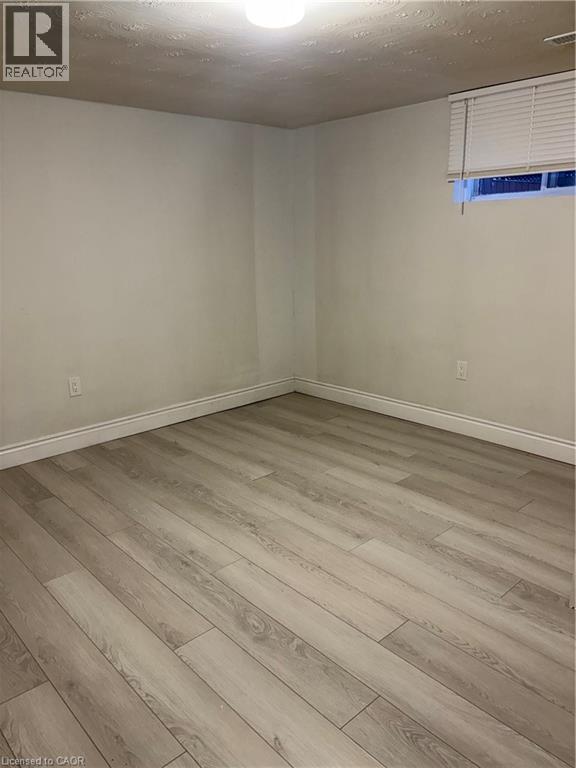 Empty room with a textured ceiling and light wood finished floors - 683 Seventh Avenue, Hamilton, ON