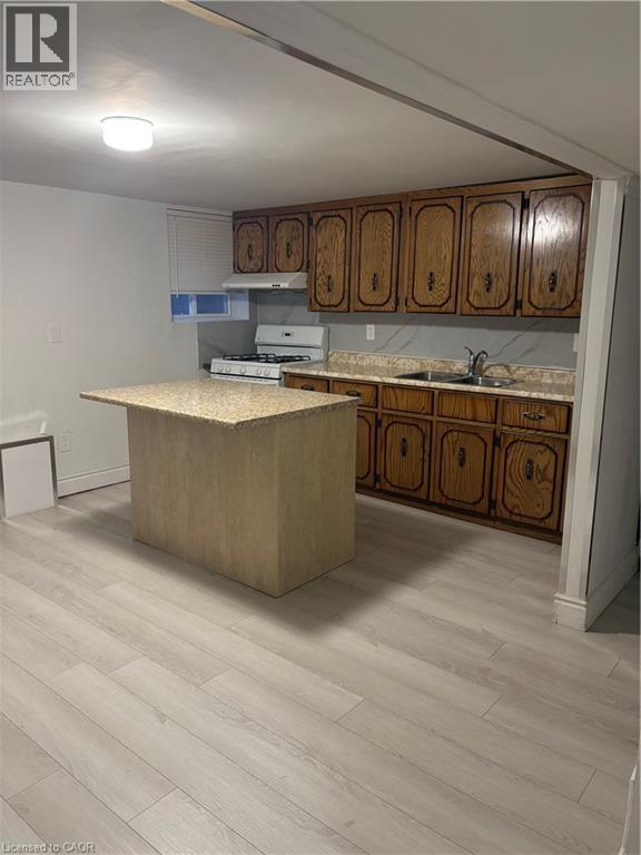 Kitchen featuring light countertops, a center island, brown cabinets, range, and light wood-style floors - 683 Seventh Avenue, Hamilton, ON