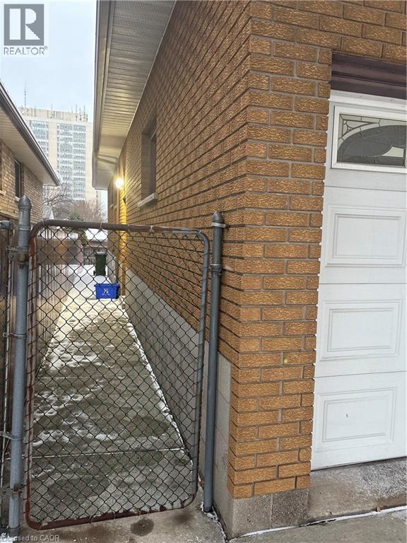 View of side of property with brick siding and a gate - 683 Seventh Avenue, Hamilton, ON