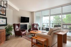 Living room with a glass covered fireplace, light wood finished floors, and expansive windows -