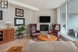 Living area with a glass covered fireplace and light wood-style floors -