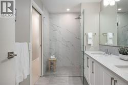 Bathroom with double vanity, light marble finish flooring, a marble finish shower, and recessed lighting -
