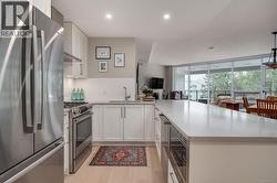 Kitchen featuring appliances with stainless steel finishes, white cabinets, backsplash, light wood-style flooring, and light stone countertops -