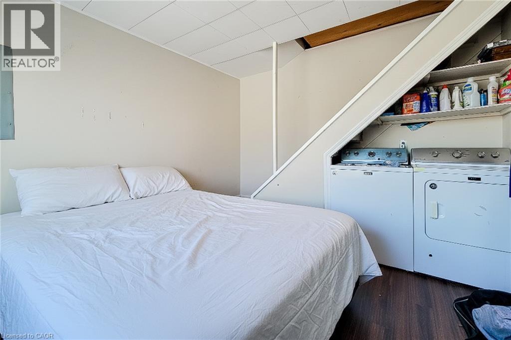 Bedroom featuring dark wood finished floors, electric panel, and washer and dryer - 558 Barnaby Street, Hamilton, ON - Indoor Photo Showing Bedroom