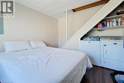 Bedroom featuring dark wood finished floors, electric panel, and washer and dryer -