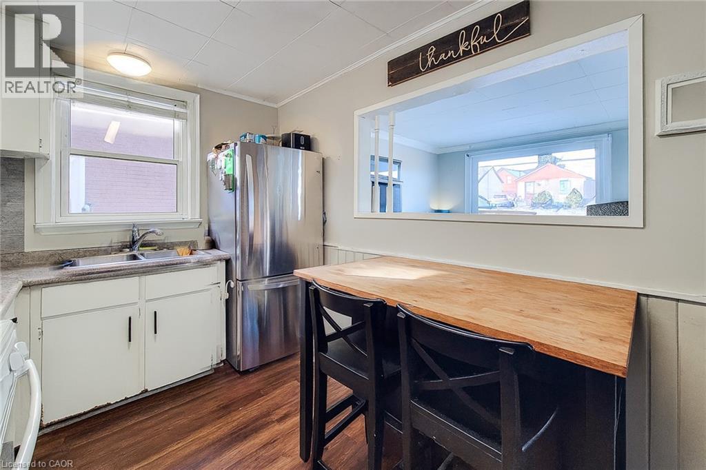 Kitchen with freestanding refrigerator, white cabinets, ornamental molding, dark wood-style floors, and healthy amount of natural light - 558 Barnaby Street, Hamilton, ON - Indoor Photo Showing Kitchen With Double Sink