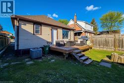 Back of property with a wooden deck, a fenced backyard, and roof with shingles -