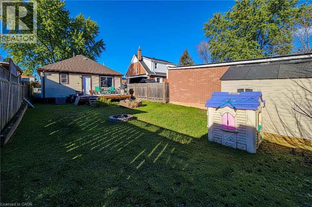Fenced backyard with an outdoor fire pit, a wooden deck, and an outdoor structure - 558 Barnaby Street, Hamilton, ON - Outdoor