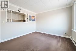 Carpeted empty room featuring ornamental molding and a baseboard heating unit -