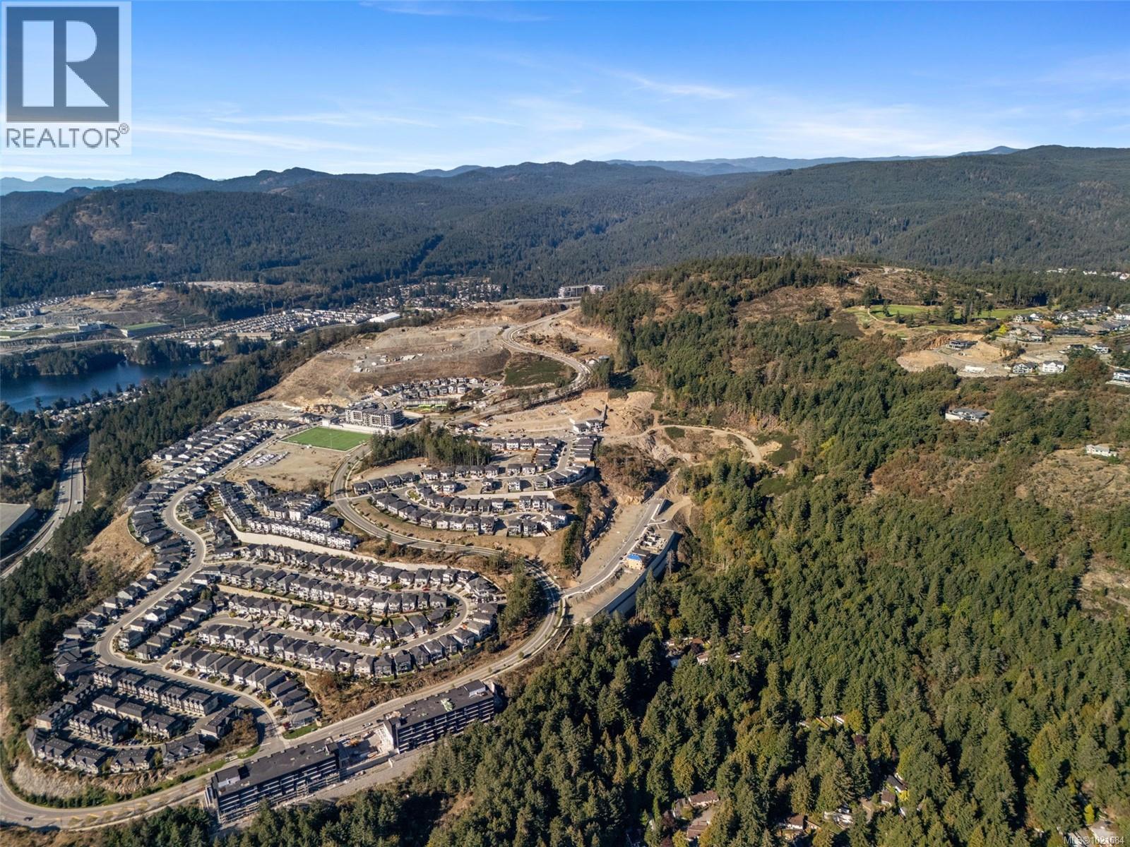Aerial overview of property's location featuring a mountain backdrop and a heavily wooded area - 1204 Cedarbrook Way, Langford, BC