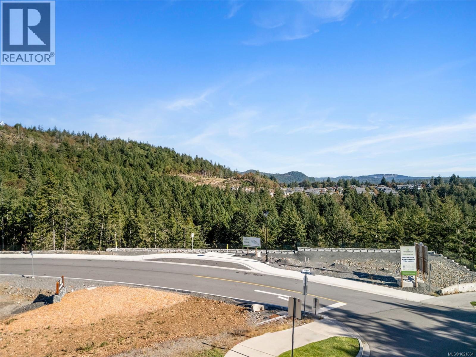 View of asphalt road with a mountain view, a view of trees, and curbs - 1204 Cedarbrook Way, Langford, BC