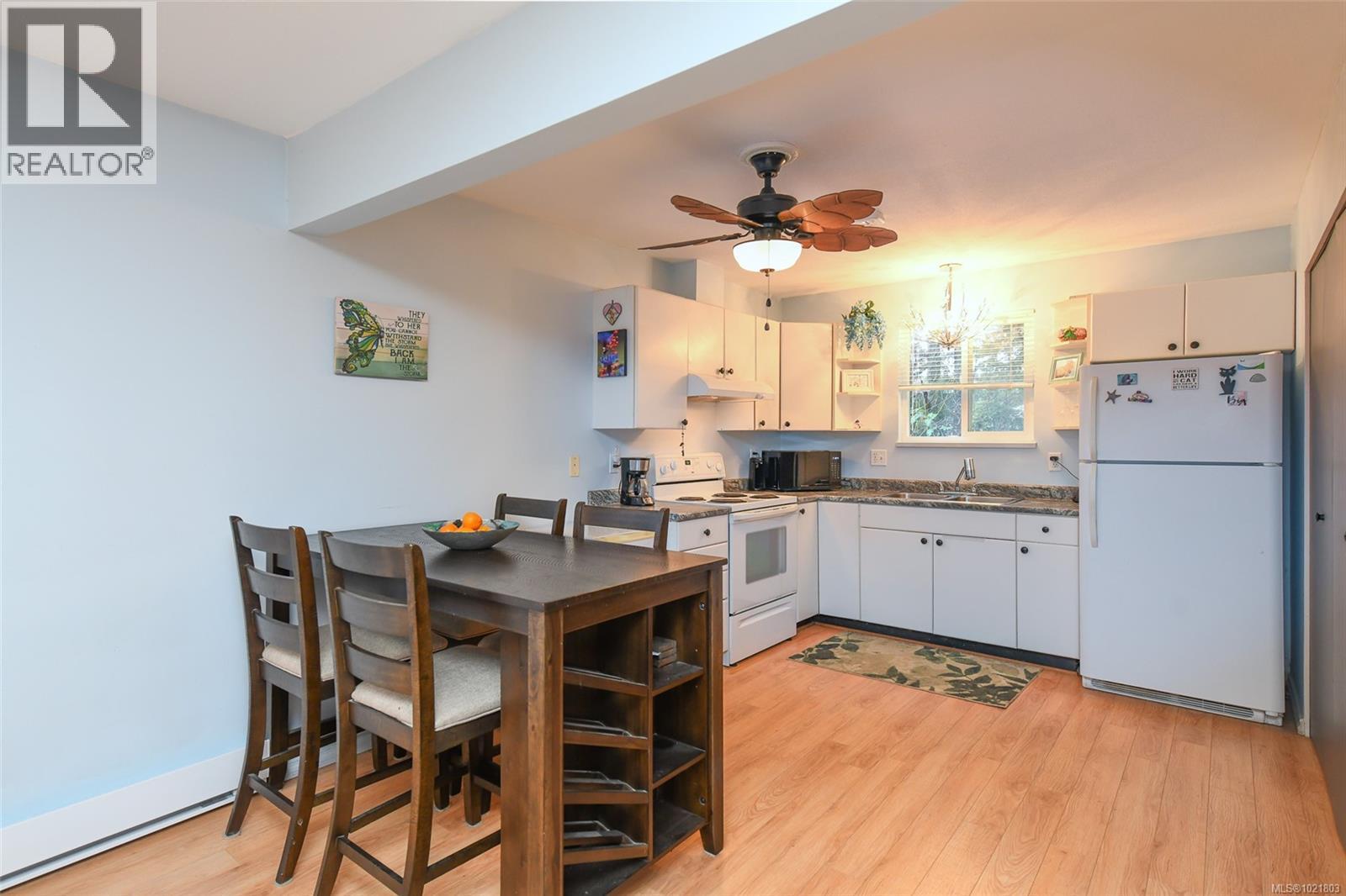 Kitchen featuring white appliances, dark countertops, white cabinetry, and light wood-style floors - 31 1535 Dingwall Rd, Courtenay, BC - Indoor