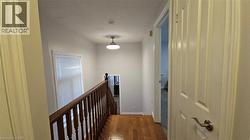 Hallway featuring an upstairs landing and dark wood-type flooring -