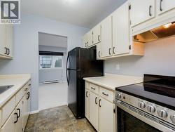 Kitchen featuring stainless steel electric range, light countertops, under cabinet range hood, baseboard heating, and white cabinets -