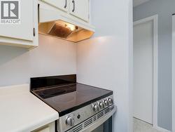 Kitchen featuring stainless steel electric range, under cabinet range hood, white cabinetry, and light countertops -