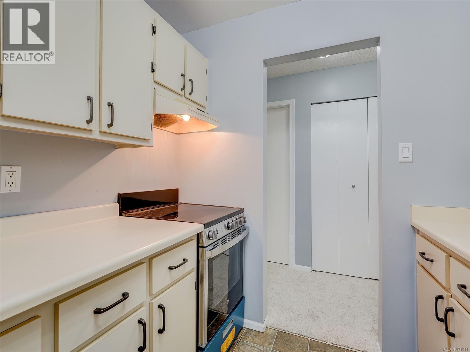 Kitchen featuring stainless steel electric range, light countertops, and under cabinet range hood - 302 859 Carrie St, Esquimalt, BC - Indoor Photo Showing Kitchen